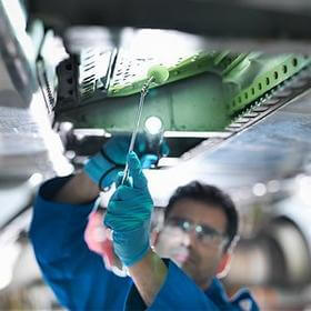 Engineer working on aircraft wing in aircraft maintenance factory, close up.